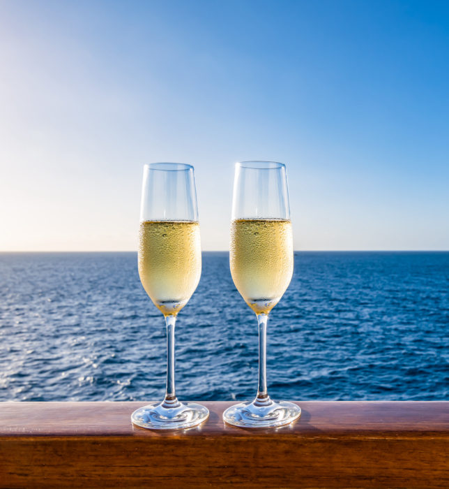 Glasses of sparkling wine on vacation. Sea background. Copy space.