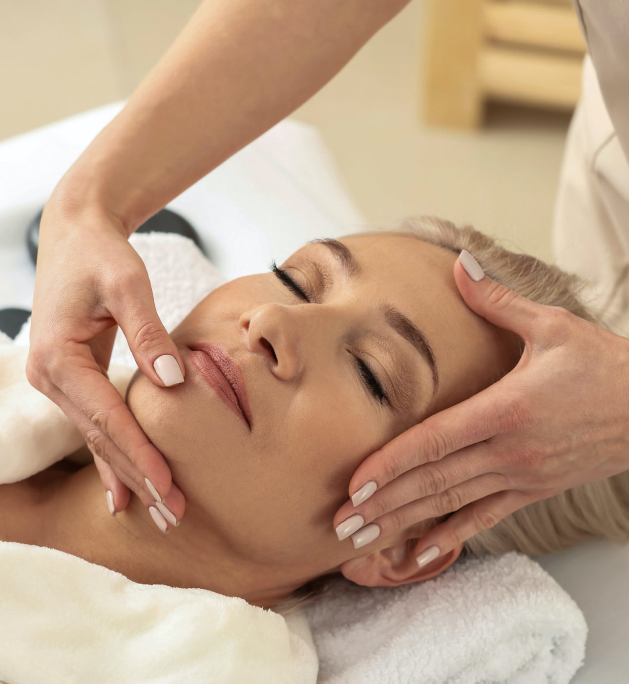 Mature woman receiving face massage in beauty salon